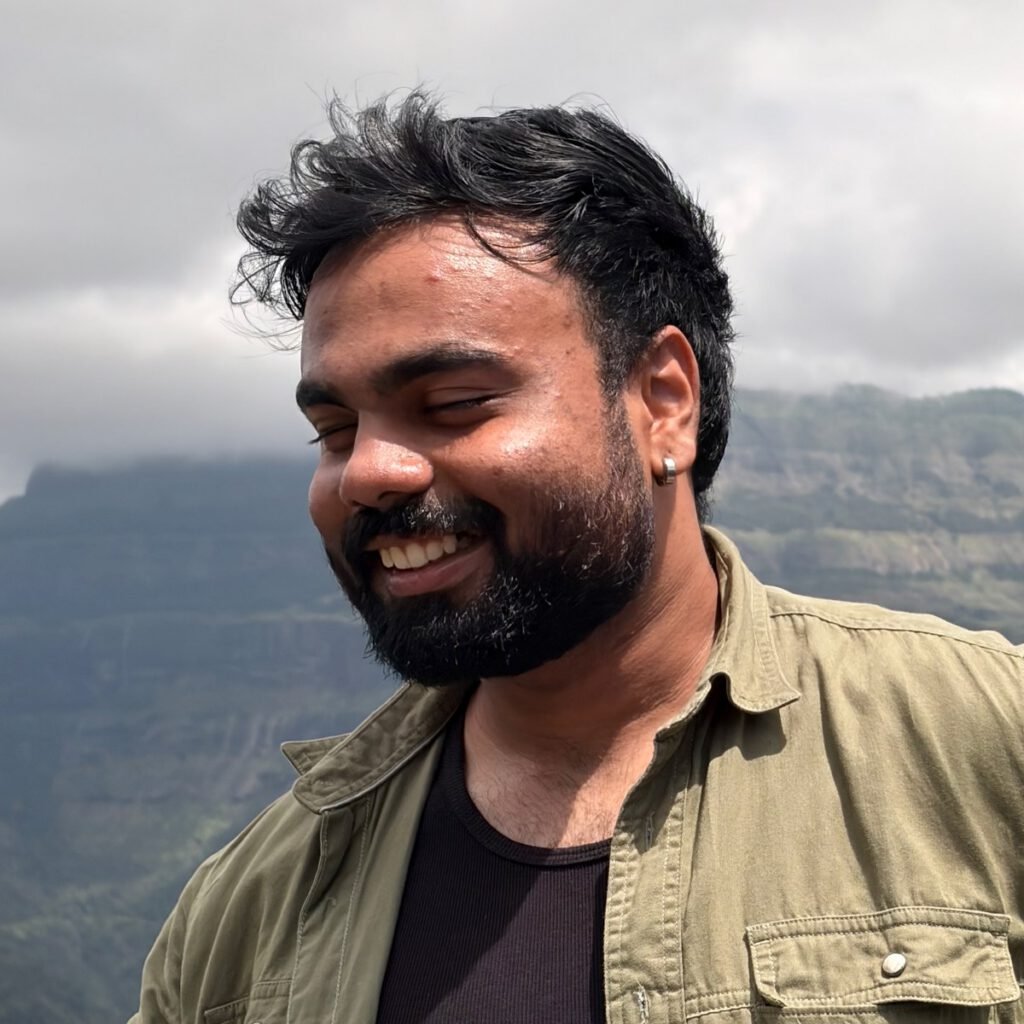 Abhinav Belhekar, smiling, with the Sahyadri cliffs behind him