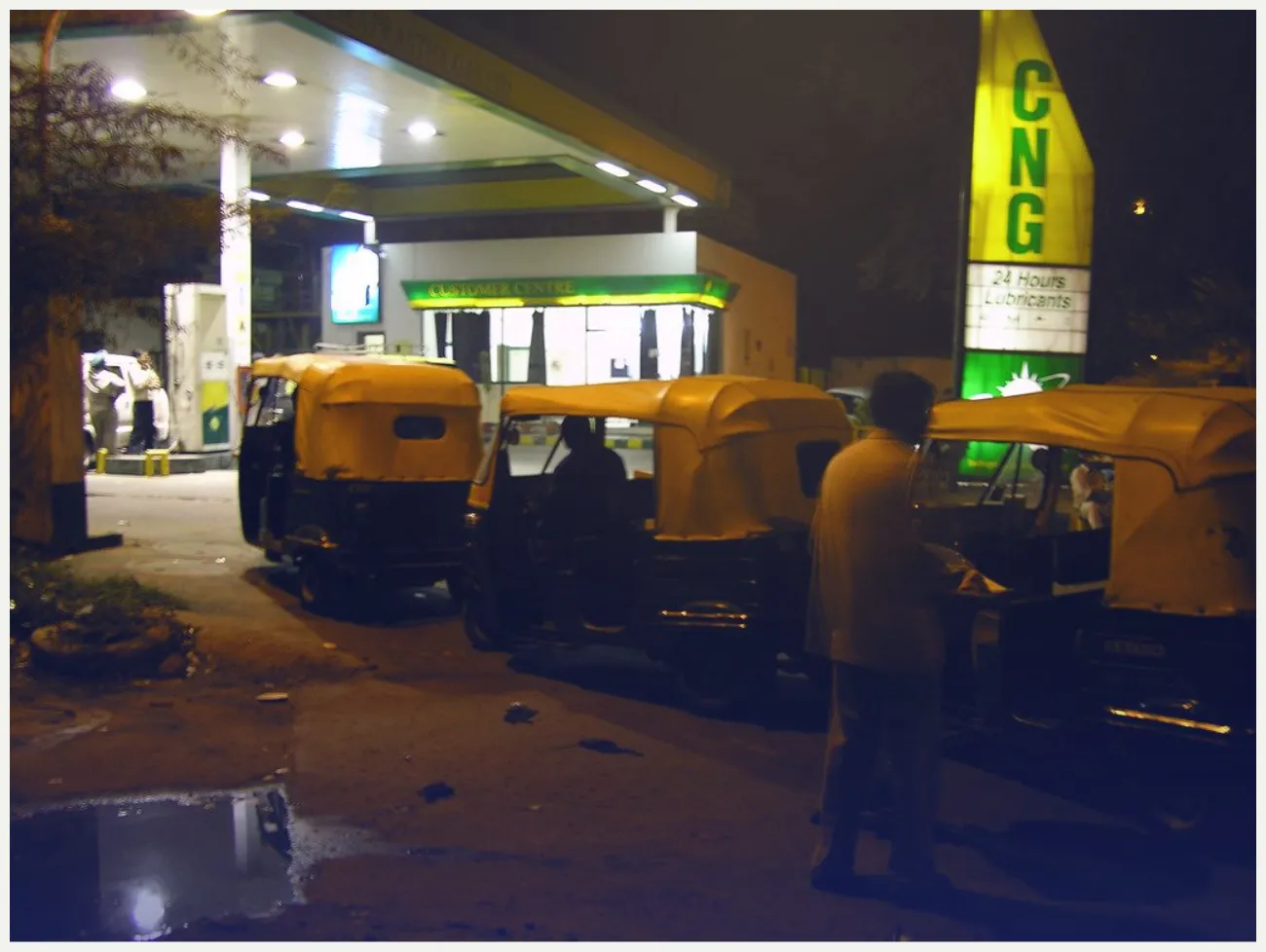 Auto rickshaws waiting in line at a CNG station at night