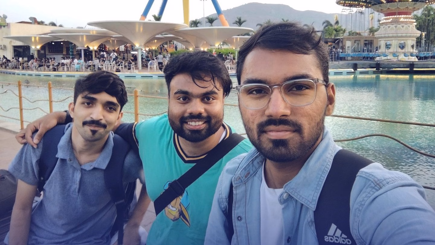 A selfie of Abhinav and two friends beside a lake at an amusement park.