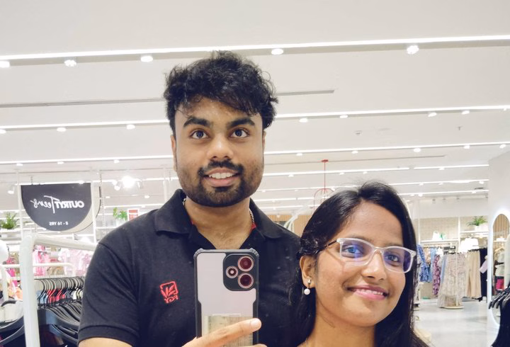 A mirror selfie of Abhinav and a friend in a clothing store.