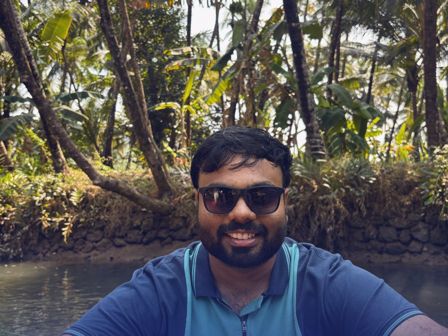 Abhinav sitting by the water in Gokarna, with palms behind him.