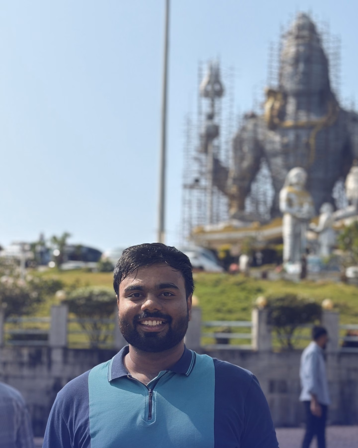 Abhinav smiling at Murudeshwar, with the giant Shiva statue behind him.