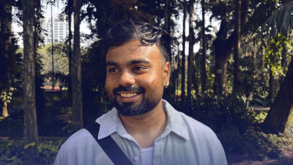 Abhinav Belhekar, smiling, under tall trees in a park